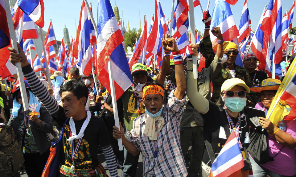 Anti-government protesters hold national flags and shout slogans during a rally in front of Grand Palace in Bangkok, Thailand, Wednesday, Jan. 15, 2014. Gunshots rang out in the heart of Thailand's capital overnight in an apparent attack on anti-government protesters early Wednesday that wounded at least two people and ratcheted up tensions in Thailand's deepening political crisis. (AP Photo/Sakchai Lalit)