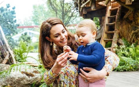 Prince Louis examines a stone in the garden with the help of his mother - Credit: Matt Porteous