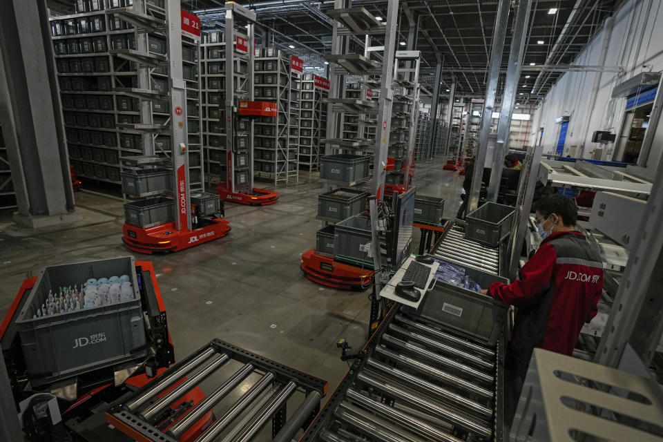 A worker and the autonomous robotic machines sort out goods at the Chinese online retailer JD.com's warehouse in Beijing on Tuesday, Nov. 9, 2021. China's biggest online shopping day, known as "Singles' Day" on Nov. 11, is taking on a muted tone this year amid a regulatory crackdown on the technology industry and President Xi Jinping's push for "common prosperity." (AP Photo/Andy Wong)