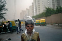<p>A young boy uses a plastic bag to protect himself from a dust storm in New Delhi on May 23, 2016. (Anindito Mukherjee/Reuters) </p>