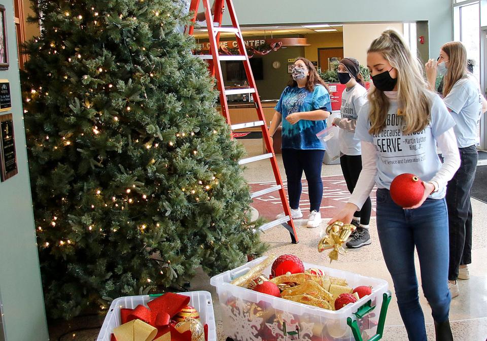 Ashland University student Zoe Webb puts the ornaments from the Kroc Center's large Christmas tree in a box as volunteers from Ashland University's AU GIVS and Black Student Alliance during their service project for MLK Day. Monday, Jan. 17, 2022. TOM E. PUSKAR/TIMES-GAZETTE.COM