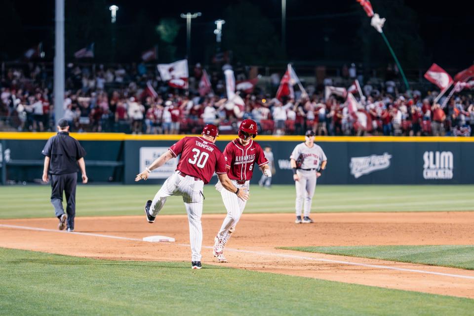 Arkansas baseball's Ben McLaughlin rounds third and celebrates with assistant coach Nate Thompson after hitting a home run in the Hogs' 9-8 win over Texas Tech Tuesday, April 16, 2024.