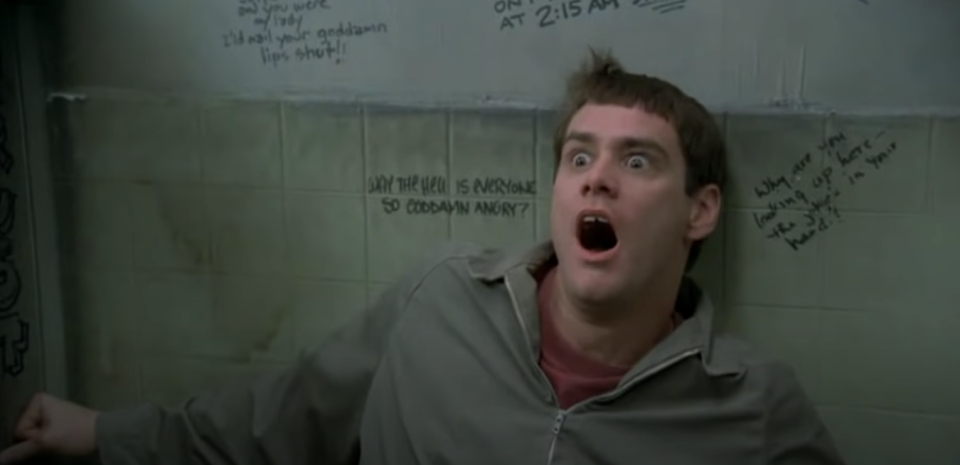 Lloyd Christmas looks terrified in a bathroom stall