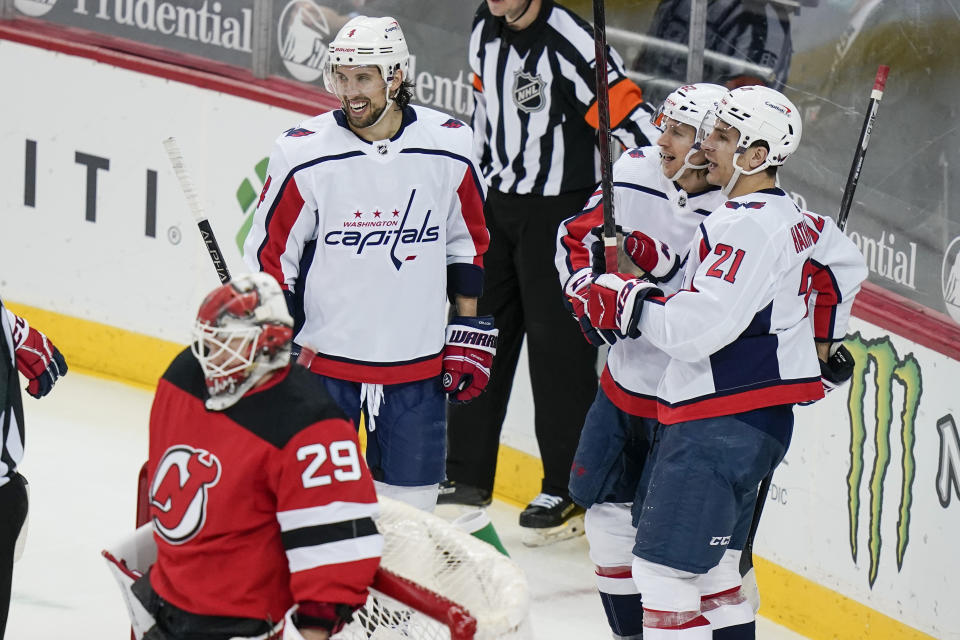 Washington Capitals' Carl Hagelin celebrates with Garnet Hathaway (21) and Brenden Dillon (4) after Hagelin scored a goal during the third period of an NHL hockey game against the New Jersey Devils on Sunday, April 4, 2021, in Newark, N.J. (AP Photo/Frank Franklin II)