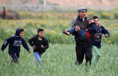 A Palestinian boy is evacuated after inhaling tear gas fired by Israeli forces during a protest at the Israel-Gaza border fence, in the southern Gaza Strip March 1, 2019. REUTERS/Ibraheem Abu Mustafa