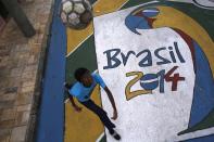 Lucas, 15, heads the ball on graffiti painted in reference to the 2014 World Cup on a street in Sao Paulo May 14, 2014. The city of Sao Paulo will host the opening match of the 2014 Brazil World Cup. REUTERS/Nacho Doce (BRAZIL - Tags: SPORT SOCCER WORLD CUP SOCIETY TPX IMAGES OF THE DAY)