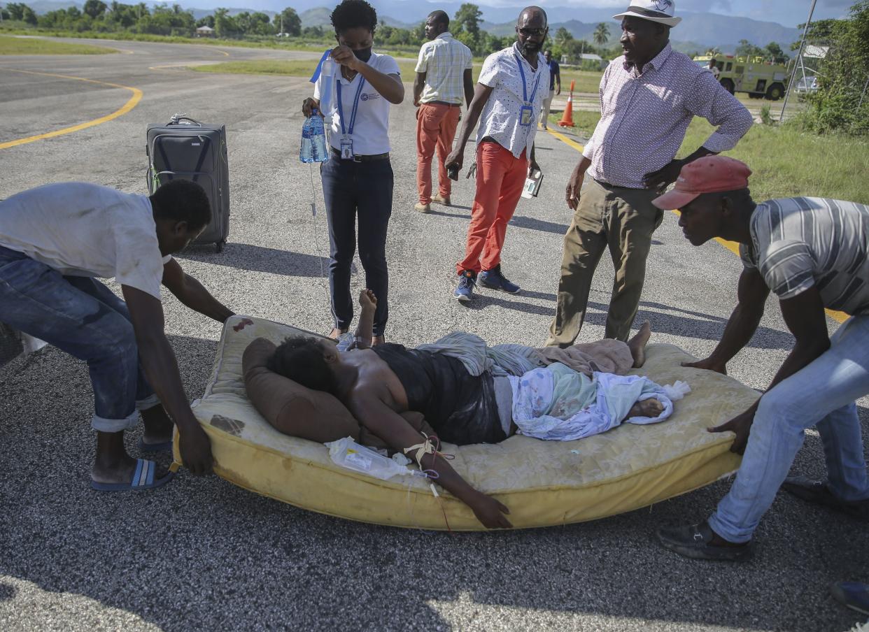 A woman injured in an earthquake is moved to a plane in Les Cayes, Haiti, Saturday, Aug. 14, 2021.