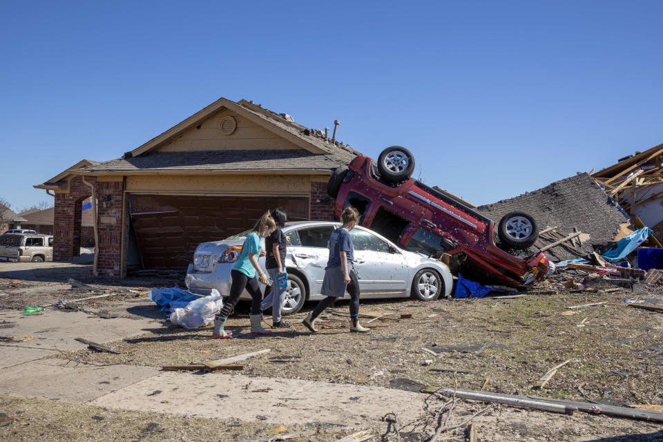 Vecinos pasan ante una casa dañada por el tiempo en Wheatland Drive y Conway Drive el lunes 27 de febrero de 2023 en Norman, Oklahoma, tras una serie de tormentas y tornados en Oklahoma durante la noche. (AP Foto/Alonzo Adams)