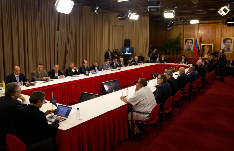 Opposition members, top, and government representatives, bottom right, meet at Miraflores presidential palace in Caracas, Venezuela, Thursday, April 10, 2014. President Nicolas Maduro and key members of the opposition met for a much-anticipated meeting aimed at reconciliation since protests began in early February. Maduro sits at the right end of the table. (AP Photo/Fernando Llano)