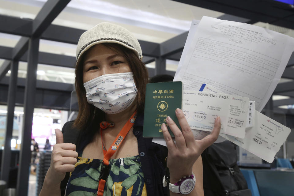 Taiwanese traveler Kuo Yitting of the first group of Palau-Taiwan Travel Corridor shows her boarding pass and a report of virus antigen test before leaving Taiwan, at Taoyuan International Airport in Taoyuan, northern Taiwan, Thursday, April 1, 2021. The Palau-Taiwan Travel Corridor, allowing people to travel between the islands without a COVID-19 quarantine, has started Thursday. (AP Photo/Chiang Ying-ying)