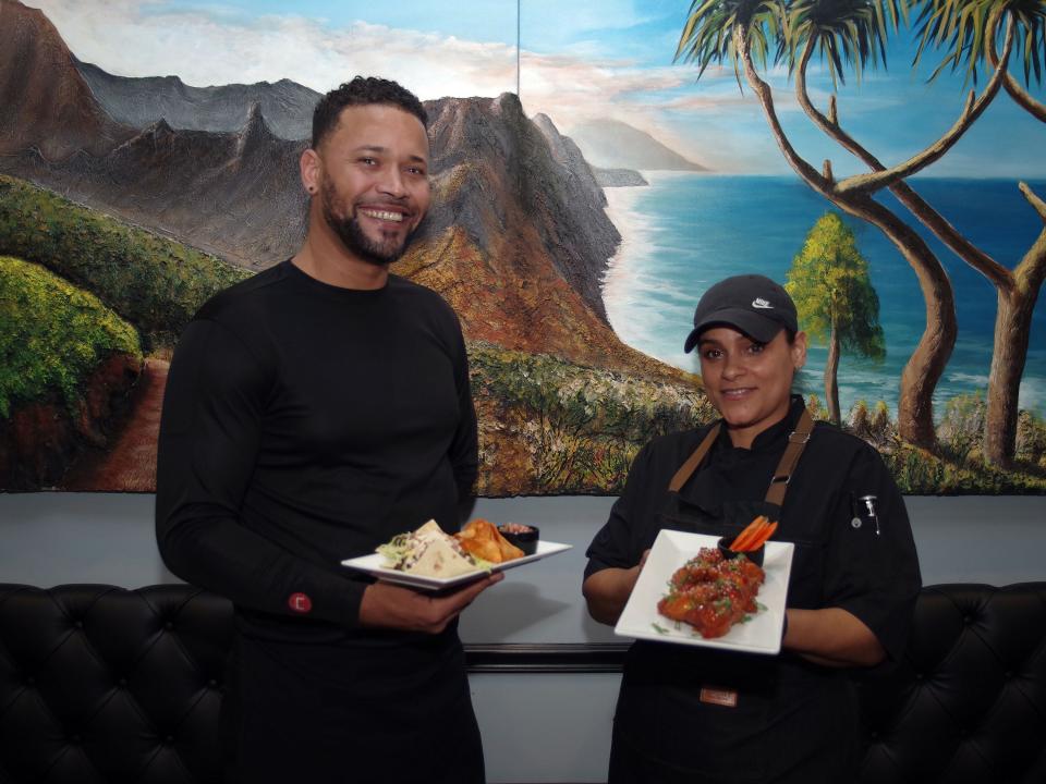 From left, Brockton Café Bar & Grill server Ailton Delgado and head chef Margarita Ramos get ready to serves dishes to customers on Wednesday, Dec. 27, 2023. Delgado is holding skirt steak tacos and Ramos is holding sweet Thai chili wings.