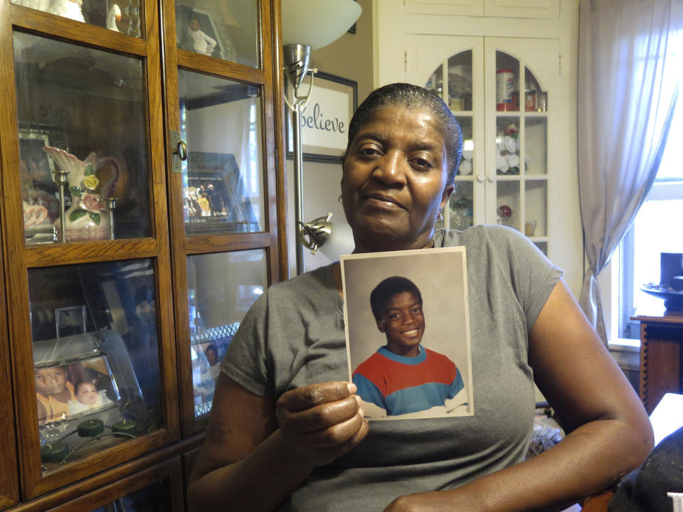 Mary Ann Riley holds a photo of her son, Adrian, in south Minneapolis on Wednesday, June 3, 2020. At 18, Adrian recalled officers becoming enraged when he refused to give up the name of a friend who ran from the cops. He said they took him to a nearby alley where they kicked and stomped him, before bringing him to the precinct. He was charged with disorderly conduct and released. Mary Ann said she found him curled up in bed, moaning in pain. Hospital staff told her there was urine in his blood, and he might have died without treatment. (AP Photo/Robin McDowell)