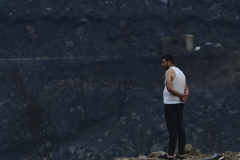 A man looks at the aftermath of a raging wildfire, in Bouira, 100 km from Algiers, Algeria, Monday, July 24, 2023. Wildfires raging across Algeria have killed at least 25 people, including soldiers trying to get the flames under control in the face of high winds and scorching summer temperatures, government ministries said Monday. (AP Photo)