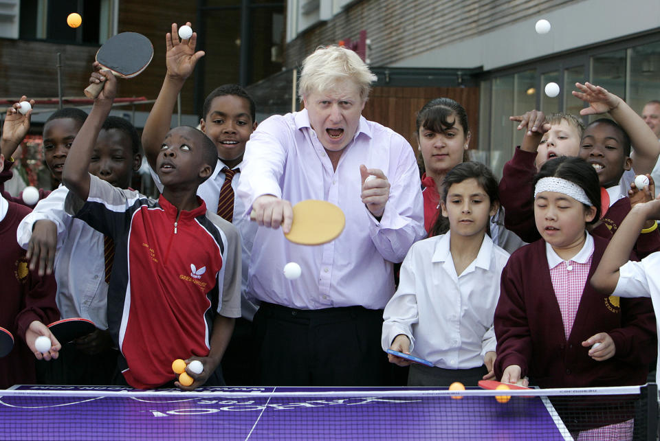 FILE - In this Friday, June 25, 2010 file photo, Mayor of London Boris Johnson, center, poses for photographers as he plays a game of table tennis with pupils in London. (AP Photo/Akira Suemori, File)