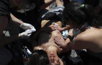 People come to the aid of an anti-government protester wounded during clashes with police amid ongoing demonstrations triggered by an increase in subway fares in Santiago, Chile, Monday, Oct. 21, 2019. Protesters defied an emergency decree and confronted police in Chile’s capital on Monday, continuing disturbances that have left at least 11 dead and led the president to say the country is “at war.” (AP Photo/Miguel Arenas)