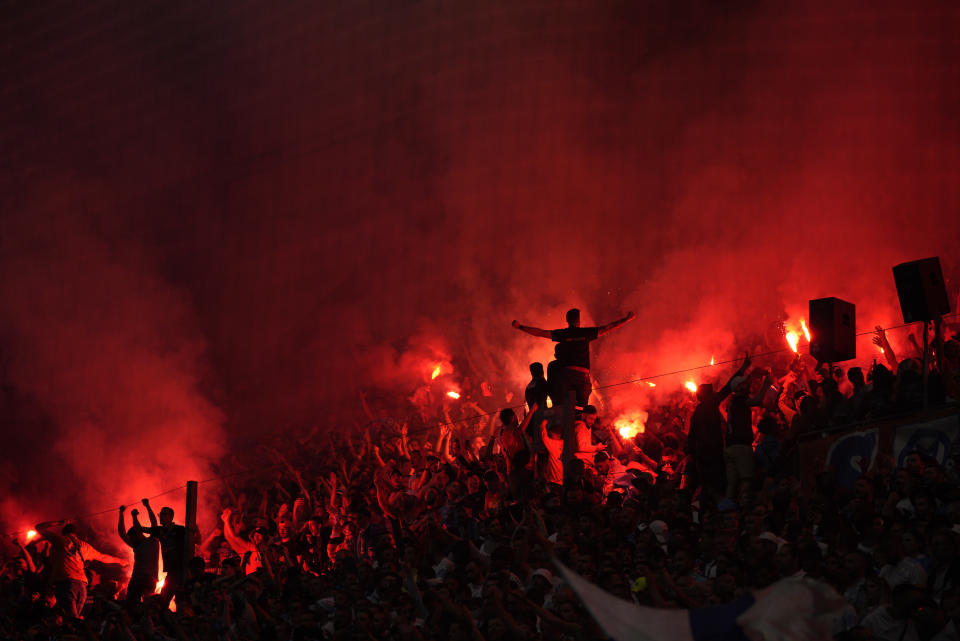 Supporters hold flares as they watch the French League One soccer match between Marseille and Lyon in Marseille, France, Sunday, May 1, 2022. (AP Photo/Daniel Cole)