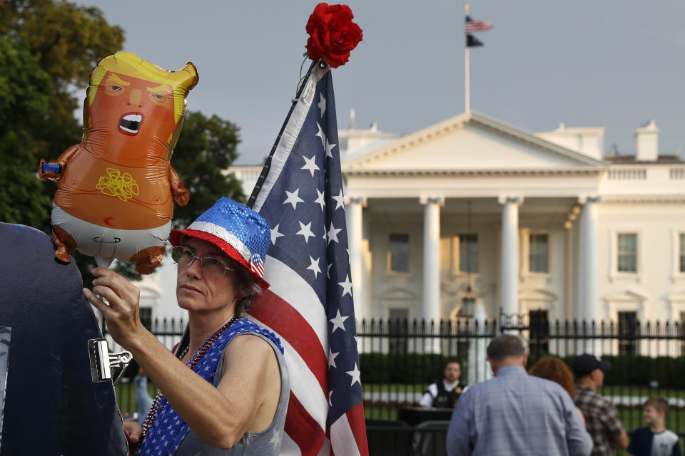 FILE - In this May 18, 2019 file photo, a woman who described herself only as "a resister" adjusts a "Trump baby" balloon at the start of a protest against President Donald Trump along Pennsylvania Ave., outside the White House in Washington. President Trump is being trolled by an angry diaper-clad caricature armed with a cell phone. It’s Baby Trump, the blimp that has become synonymous with resistance to the American president. The balloon has been cloned multiples times over and become something of a celebrity _ for at least one slice of the U.S. electorate. He’s also emerged as a rallying point for supporters of the president who see the blimp as evidence of just how over-the-top the opposition has become. (AP Photo/Jacquelyn Martin)