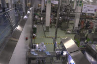 In this Thursday, Feb. 27, 2020, photo, a worker checks yogurt coming off the production line at the Mengniu dairy factory in Beijing. Reporters were invited to China Mengniu Dairy Co. Ltd. this week to be shown how companies are reviving after anti-virus measures shut down most of the world's second-biggest economy. (AP Photo/Ng Han Guan)