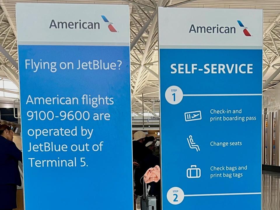 Sign at the American Airlines check-in at Terminal 8 telling passengers that some AA flights are operated by JetBlue out of Terminal 5.