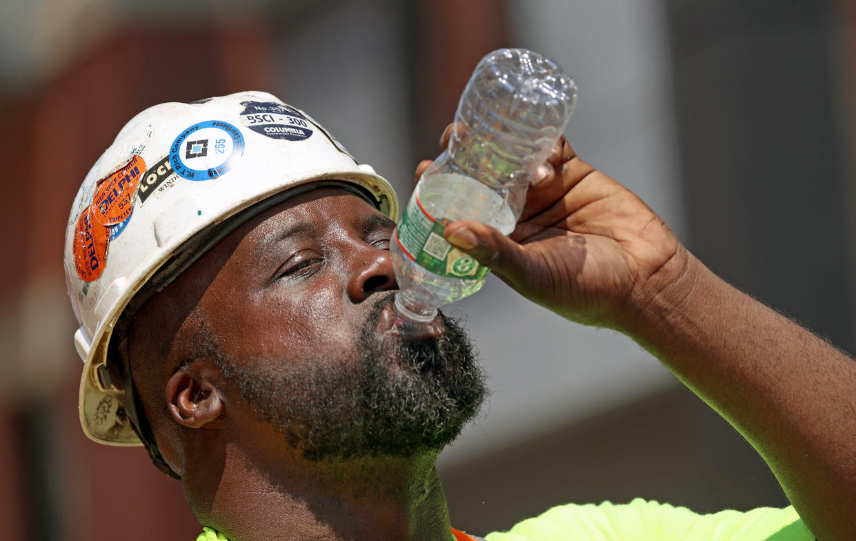 A construction worker drains a bottle of water while working 