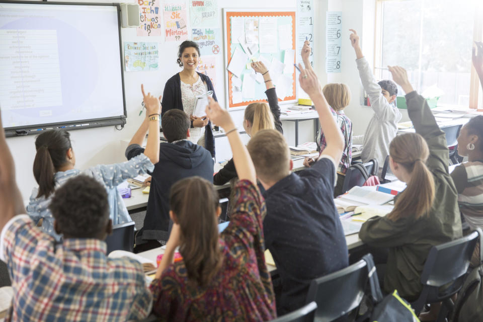 students raising their hands in a classroom