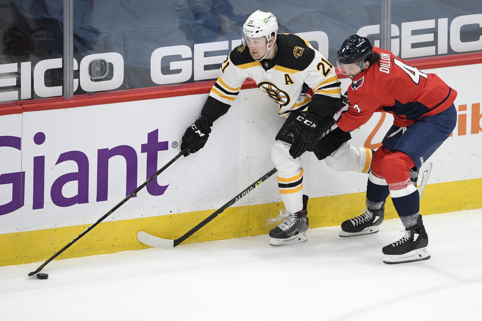 Boston Bruins left wing Nick Ritchie (21) and Washington Capitals defenseman Brenden Dillon (4) battle for the puck during the first period of an NHL hockey game, Tuesday, May 11, 2021, in Washington. (AP Photo/Nick Wass)