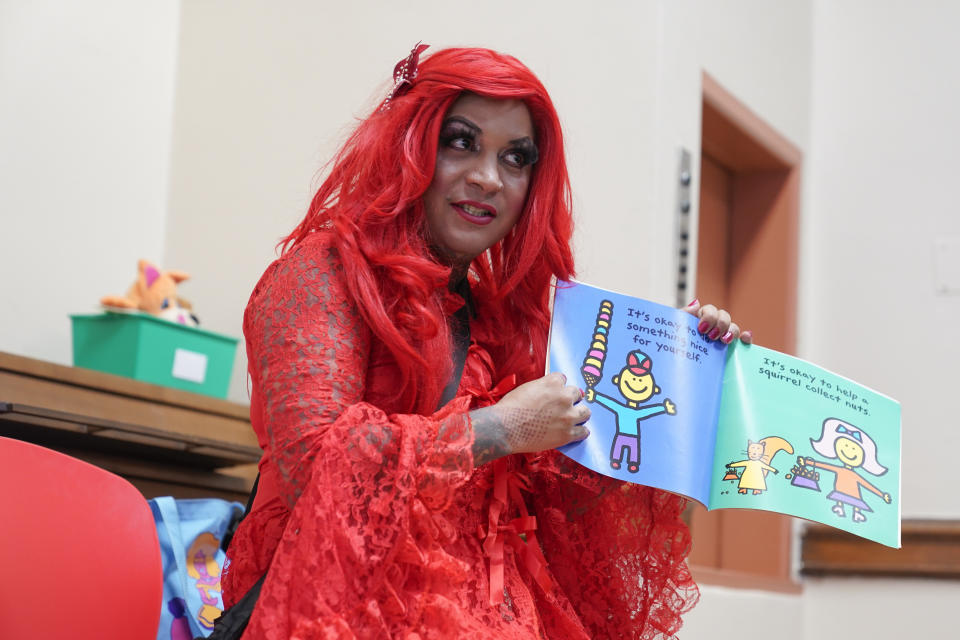 A drag queen who goes by the name Flame reads stories to children and their caretakers during a Drag Story Hour at a public library in New York, Friday, June 17, 2022. (AP Photo/Seth Wenig)