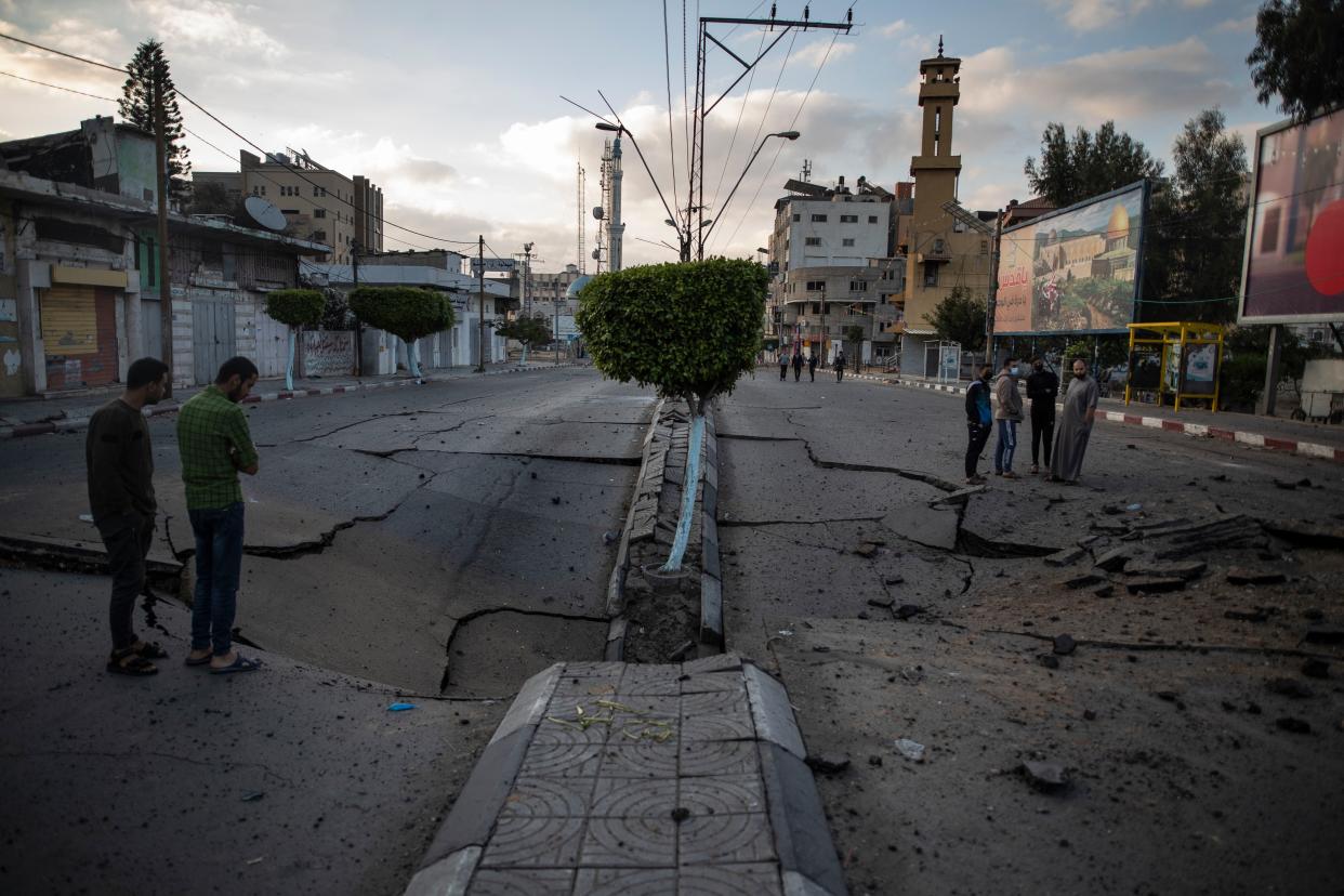 Palestinians walk along a destroyed road following Israeli airstrikes on Gaza City on Thursday, May 13, 2021.