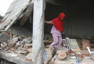 Earthquake survivor Fakriyah tries to balance herself as she walks on the rubble at her shop damaged during Wednesday's earthquake in Tringgading, Aceh province, Indonesia, Friday, Dec. 9, 2016. Over a hundred people were killed in the quake that hit the northeast of the province on Sumatra before dawn Wednesday. Hundreds of people were injured and thousands buildings destroyed or heavily damaged. (AP Photo/Binsar Bakkara)