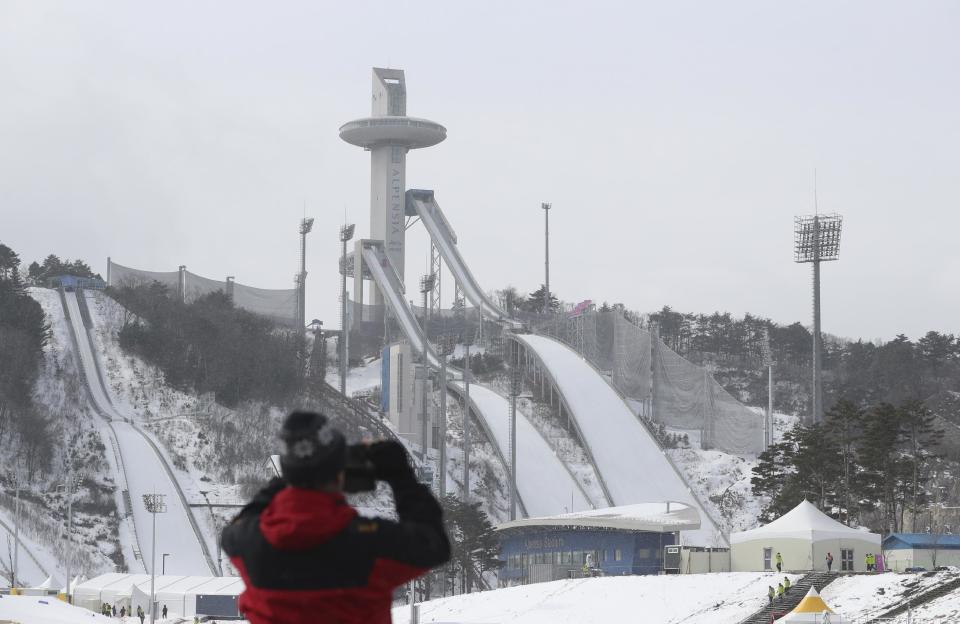 In this Sunday, Feb. 5, 2017 photo, a visitor takes a photo of the Alpensia Ski Jumping Center where is a venue for the 2018 Pyeongchang Winter Olympics in Pyeongchang, South Korea. One year before the Olympics, the country is in political disarray, and winter sports are the last thing on many people’s minds. To say that South Koreans are distracted from what had been billed as a crowning sports achievement is an understatement. (AP Photo/Lee Jin-man)