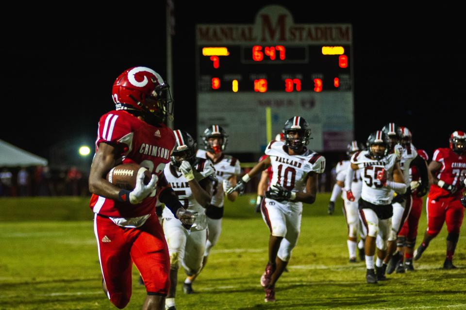 Manual High School running back Zah’Ron Washburn looks back at the Ballard defense as he runs for a touchdown during a football game Friday, Sept. 23, 2022. The Crimsons defeated the Bruins 21-0.