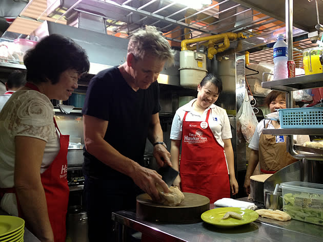 Tian Tian Chicken Rice founder chef Foo Kui Lian looks on as celebrity chef Gordon Ramsay chops a piece of chicken. (Yahoo! photo)