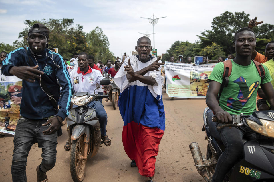 Young men chant slogans against the power of Lieutenant-Colonel Damiba, against France and pro-Russia, in Ouagadougou, Burkina Faso, Friday Sept. 30, 2022. Residents say gunfire rang out early in the morning and the state broadcaster has gone off the air, fueling fears that another coup is underway. The developments Friday come just after coup leader-turned-president, Lt. Col. Paul Henri Sandaogo Damiba, returned from a trip to the U.N. General Assembly. (AP Photo/Sophie Garcia)