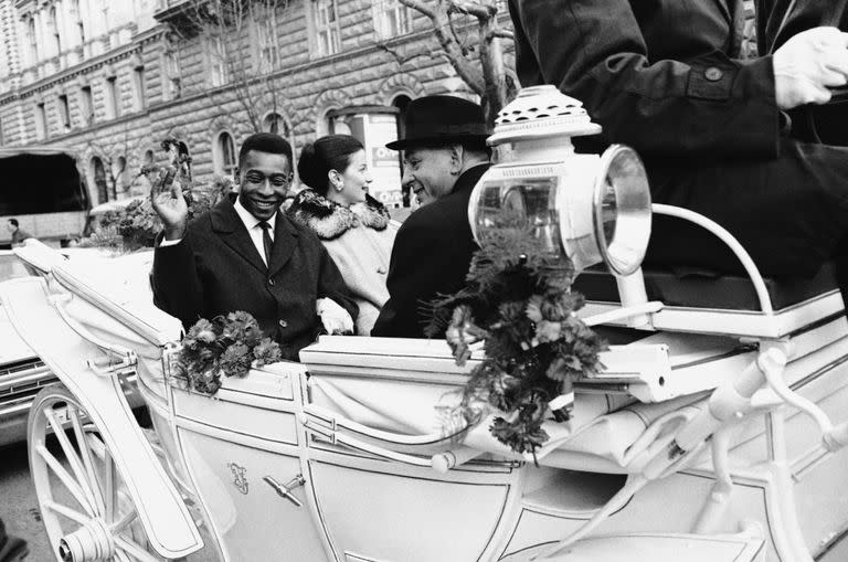 La estrella del fútbol brasileño Pelé saluda a sus admiradores mientras él y su novia Rosemeri viajan en un tradicional carruaje tirado por caballos mientras recorren Salzburgo, Austria, el 25 de febrero de 1966