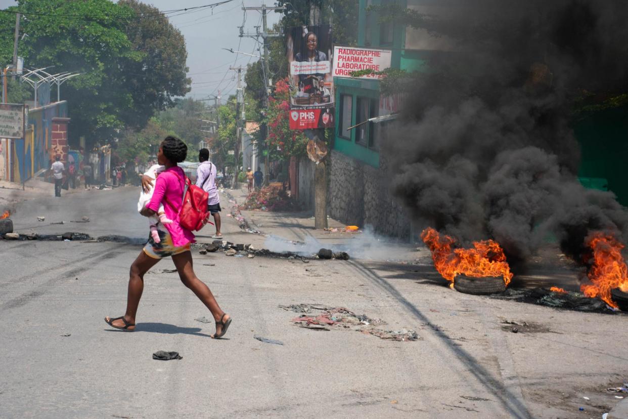 <span>A woman carrying a child runs from the area after gunshots were heard in Port-au-Prince, Haiti, 20 March 2024.</span><span>Photograph: Clarens Siffroy/AFP/Getty Images</span>