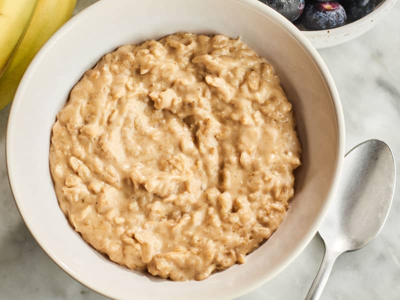 peanut butter oatmeal in a bowl with fruit and honey near it