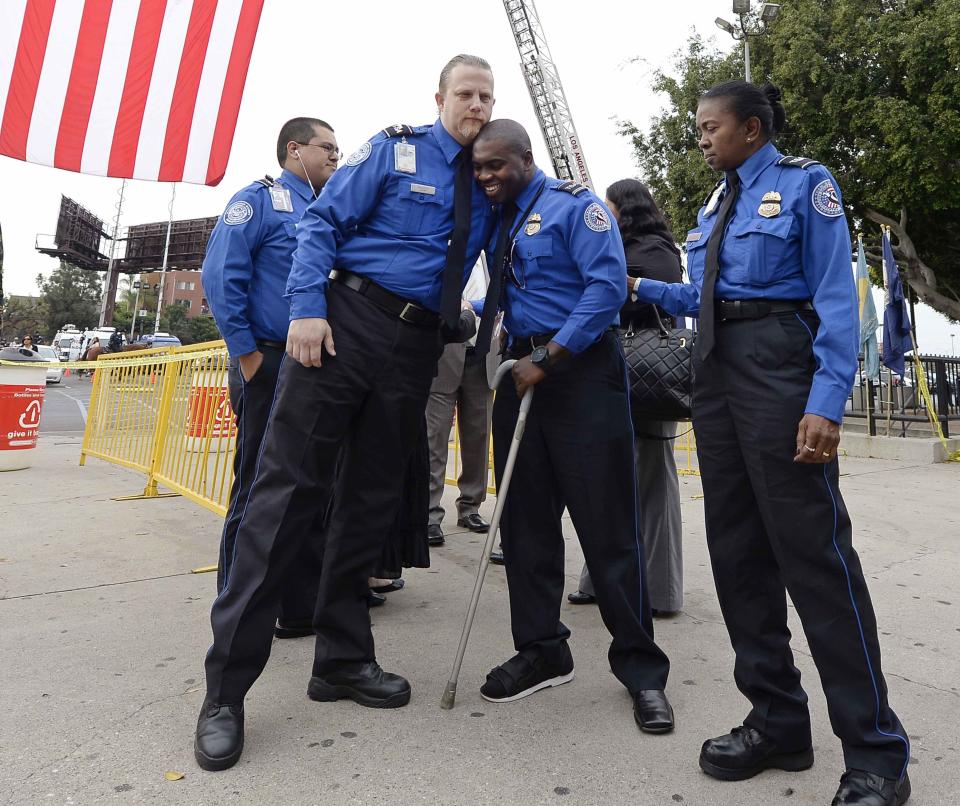 Injured TSA agent Grigsby gets a hug from a fellow agent as they arrive for a memorial service for their colleague Hernandez in Los Angeles