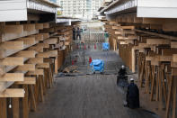 Construction workers fold a tarp sheet at a closed building complex being built as part of the athletes' village to be used during the postponed Tokyo 2020 Olympic and Paralympic Games, in Tokyo Thursday, April 8, 2021. Many preparations are still up in the air as organizers try to figure out how to hold the postponed games in the middle of a pandemic. (AP Photo/Hiro Komae)