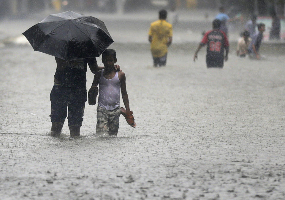 <p>Anwohner laufen durch die überfluteten Straßen in Mumbai. Indien befindet sich gerade mitten in der Monsunzeit, die noch bis September anhält. (Bild: AP Photo/Rafiq Maqbool) </p>