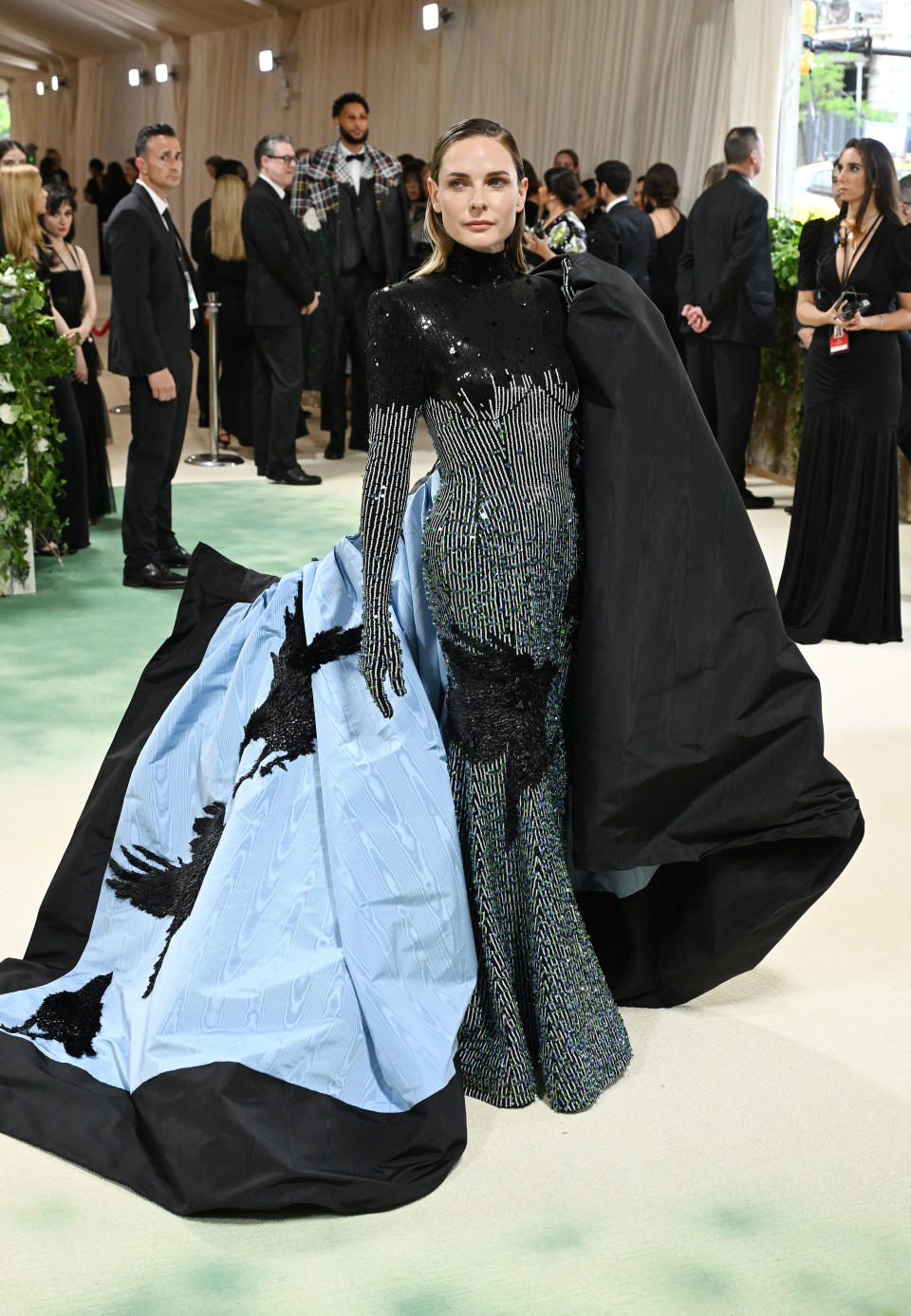 Rebecca Ferguson at the Met Gala in a dramatic gown featuring a bird motif that was revealed after removing her coat
