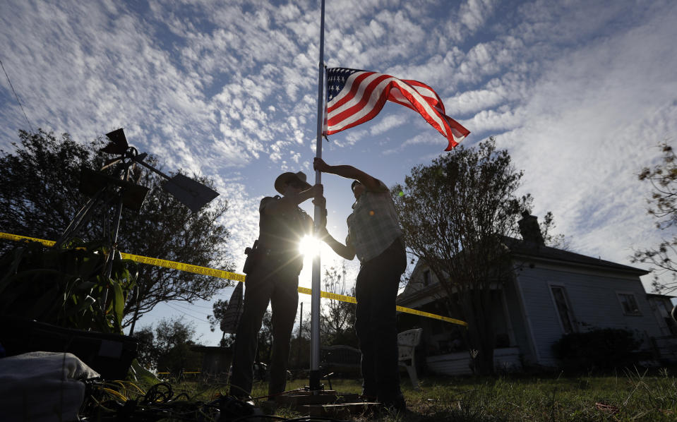 <p>A law enforcement officer helps a man changes a flag to half-staff near the scene of a shooting at the First Baptist Church of Sutherland Springs to honor victims, Monday, Nov. 6, 2017, in Sutherland Springs, Texas. (Photo: Eric Gay/AP) </p>