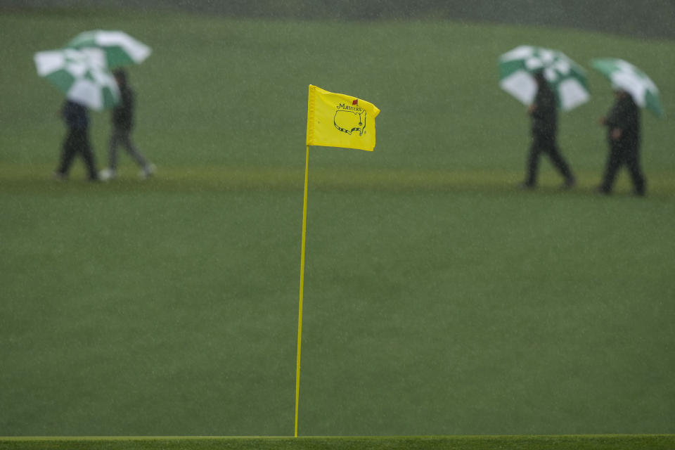 Patrons cross the 15th fairway during the weather delayed third round of the Masters golf tournament at Augusta National Golf Club on Saturday, April 8, 2023, in Augusta, Ga. (AP Photo/Charlie Riedel)
