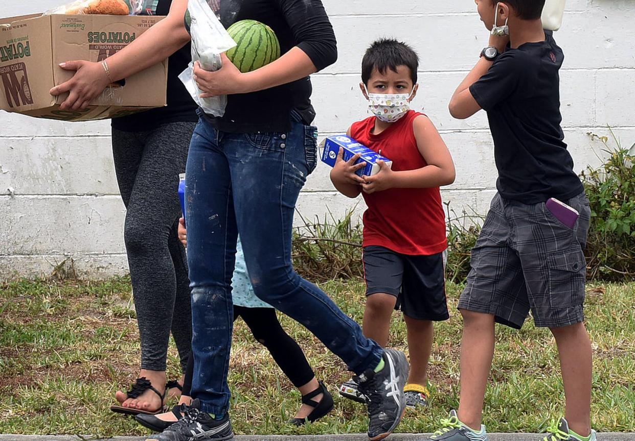 <span class="caption">Despite help from the government and charities, the number of food-insecure kids is rising.</span> <span class="attribution"><a class="link " href="https://www.gettyimages.com/detail/news-photo/women-and-children-wearing-protective-face-masks-carry-food-news-photo/1209343192" rel="nofollow noopener" target="_blank" data-ylk="slk:NurPhoto/Getty Images;elm:context_link;itc:0;sec:content-canvas"> NurPhoto/Getty Images</a></span>