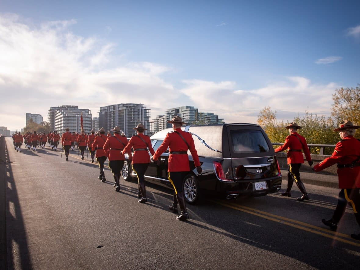 A hearse carries Const. Shaelyn Yang's flag-draped casket through the streets of Richmond, B.C., as the procession makes its way to the funeral ceremony. (Justine Boulin/CBC - image credit)