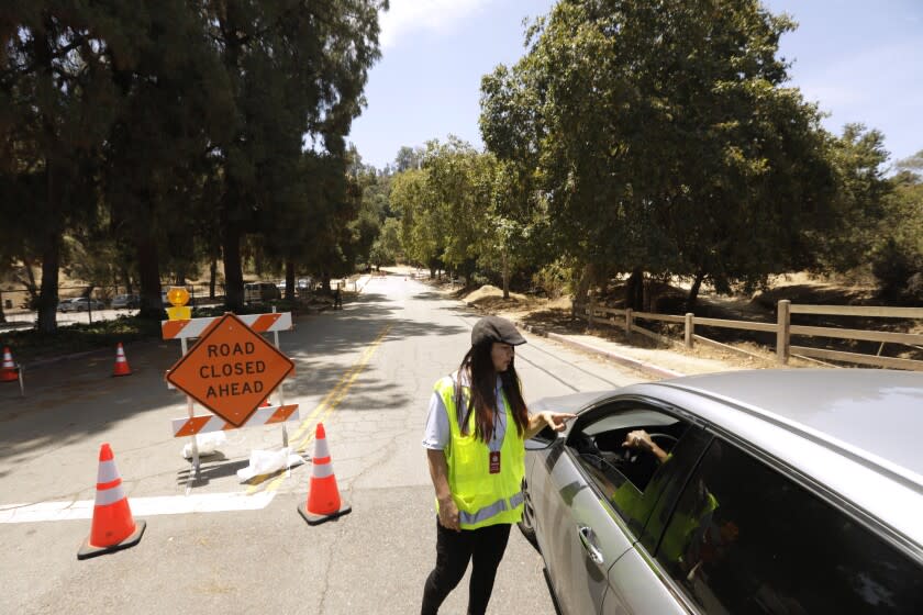 LOS ANGELES, CA - JUNE 29, 2022 - - City worker Emma Delgado tells a driver that motorists are not allowed to drive down this one-third mile portion of Griffith Park Drive in Griffith Park in Los Angeles on June 29, 2022. The street is closed to improve safety for pedestrians and cyclists. The road is known to draw high-speed drivers who are looking for a shortcut, avoiding the 134 and 5 freeways. The temporary closure has been in place since Monday, June 27 and will carry on indefinitely until more permanent changes to the park's infrastructure are in place. (Genaro Molina / Los Angeles Times)