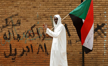 A protester makes victory sign as he carries a Sudanese flag in front of the Defence Ministry in Khartoum, Sudan, April 19, 2019. REUTERS/Umit Bektas/Files