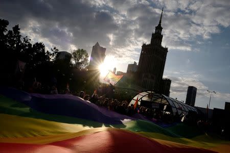 People hold a large rainbow flag at a protest in support of Elzbieta Podlesna, the author of an image depicting the Virgin Mary with a rainbow-coloured halo, reminiscent of the LGBT flag, who was detained for offending religious beliefs, in Warsaw, Poland May 7, 2019. REUTERS/Kacper Pempel