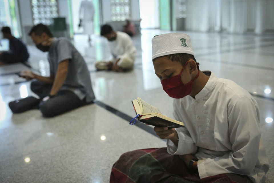Muslim men wearing face masks as a precaution against coronavirus men read the holy book of Quran during the first day of the holy fasting month of Ramadan at a mosque in the religiously conservative province of Aceh, Indonesia, Friday, April 24, 2020. During Ramadan, which begins Friday, faithful Muslims normally fast during the day and then congregate for night prayers and share communal meals. (AP Photo/Heri Juanda)