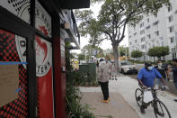 *A man leaves Marcus Samuelsson's Red Rooster Restaurant after getting a free meal during the new coronavirus pandemic, Monday, April 6, 2020, in the Overtown neighborhood of Miami. Samuelsson has partnered with chef Jose Andres' World Central Kitchen to distribute meals to those in need. (AP Photo/Lynne Sladky)