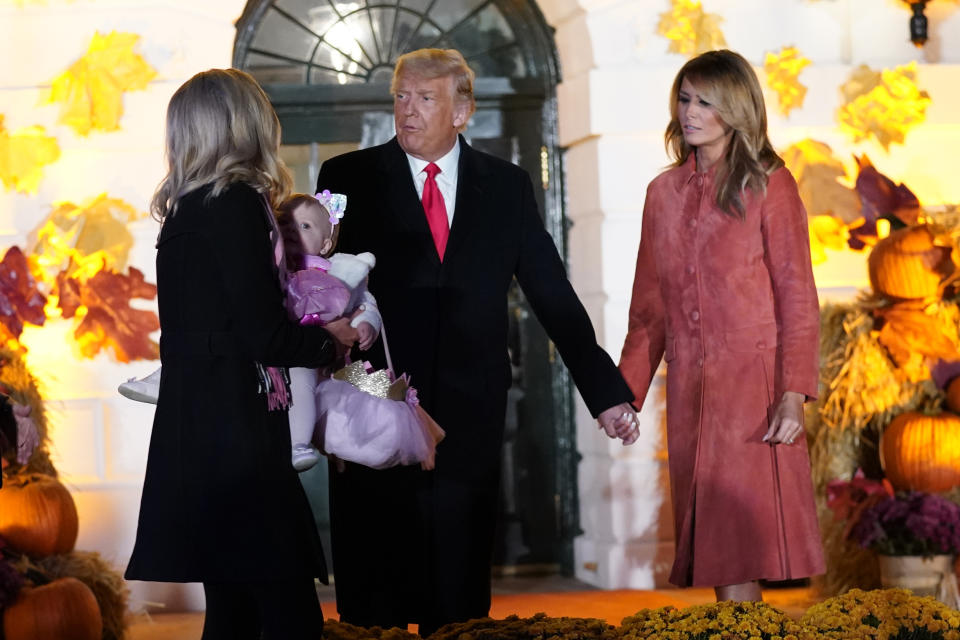 President Donald Trump and first lady Melania Trump pose for a photo with White House press secretary Kayleigh McEnany, holding her 11-month-old daughter, as they greet trick-or-treaters on the South Lawn during a Halloween celebration at the White House, Sunday, Oct. 25, 2020, in Washington. (AP Photo/Manuel Balce Ceneta)